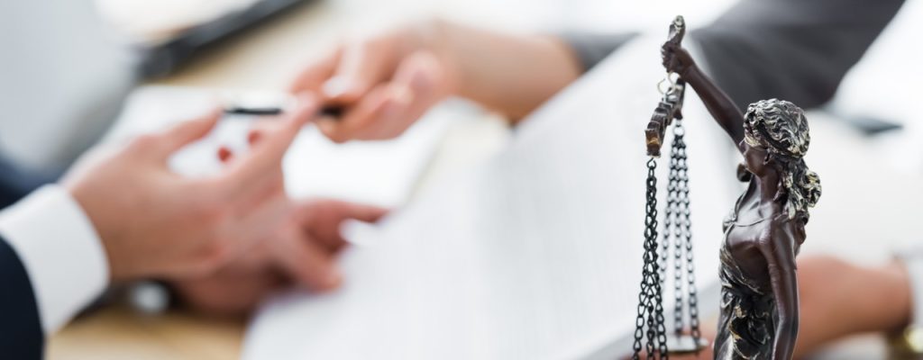 selective focus of themis figurine and businesspeople signing contract