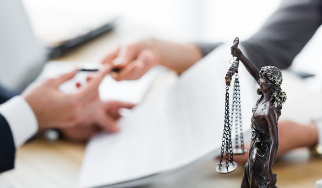 selective focus of themis figurine and businesspeople signing contract